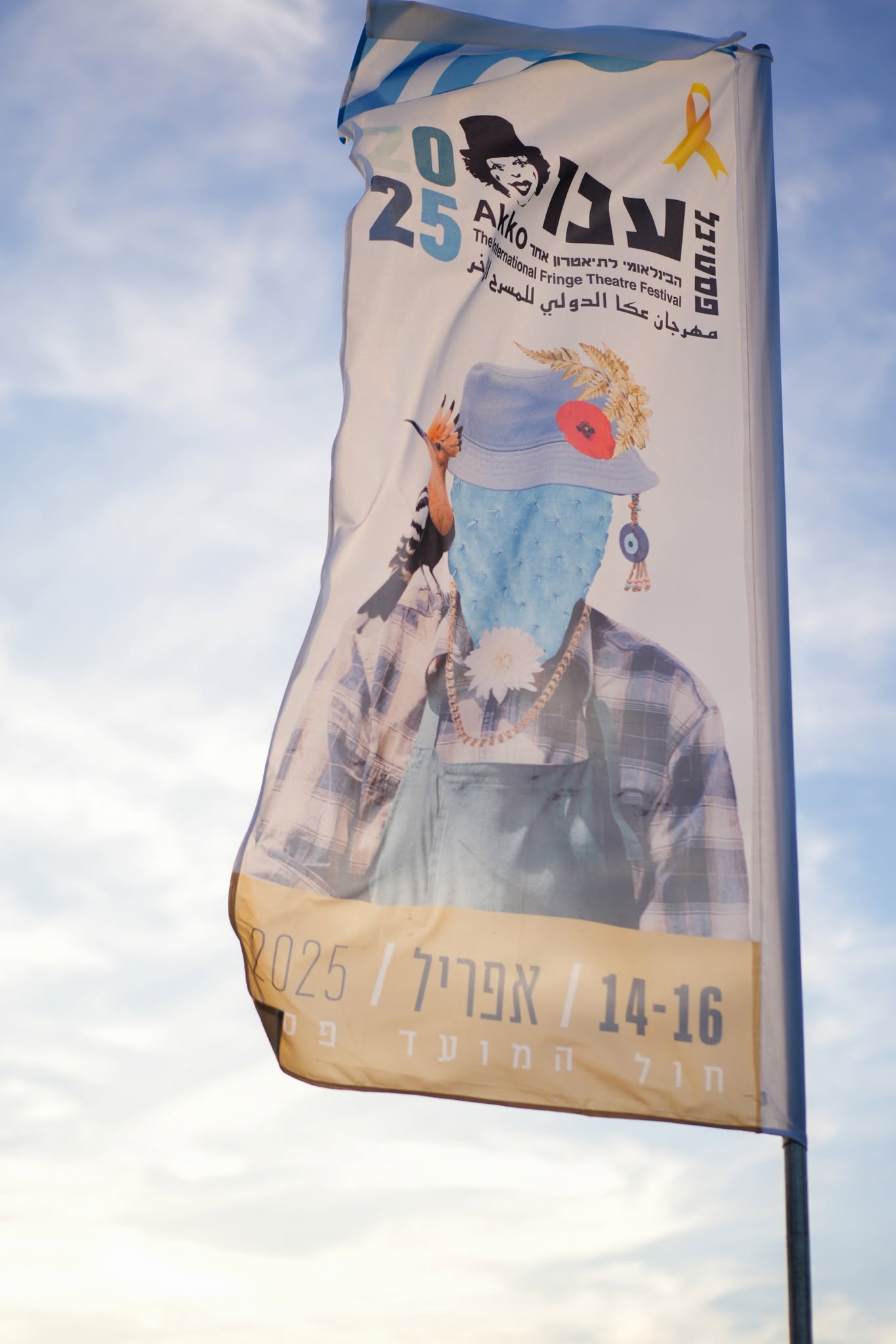 דגל פסטיבל עכו מתנופף מול שמיים בהירים.