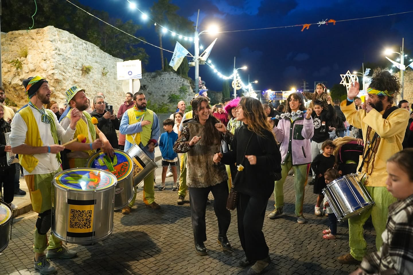 נגני כלי הקשה מובילים תהלוכה ברחובות העיר בלילה.