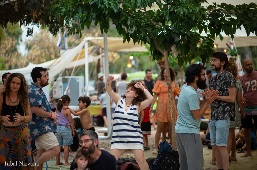 משפחות רוקדות ונפגשות בין עצים בשטח הפסטיבל.