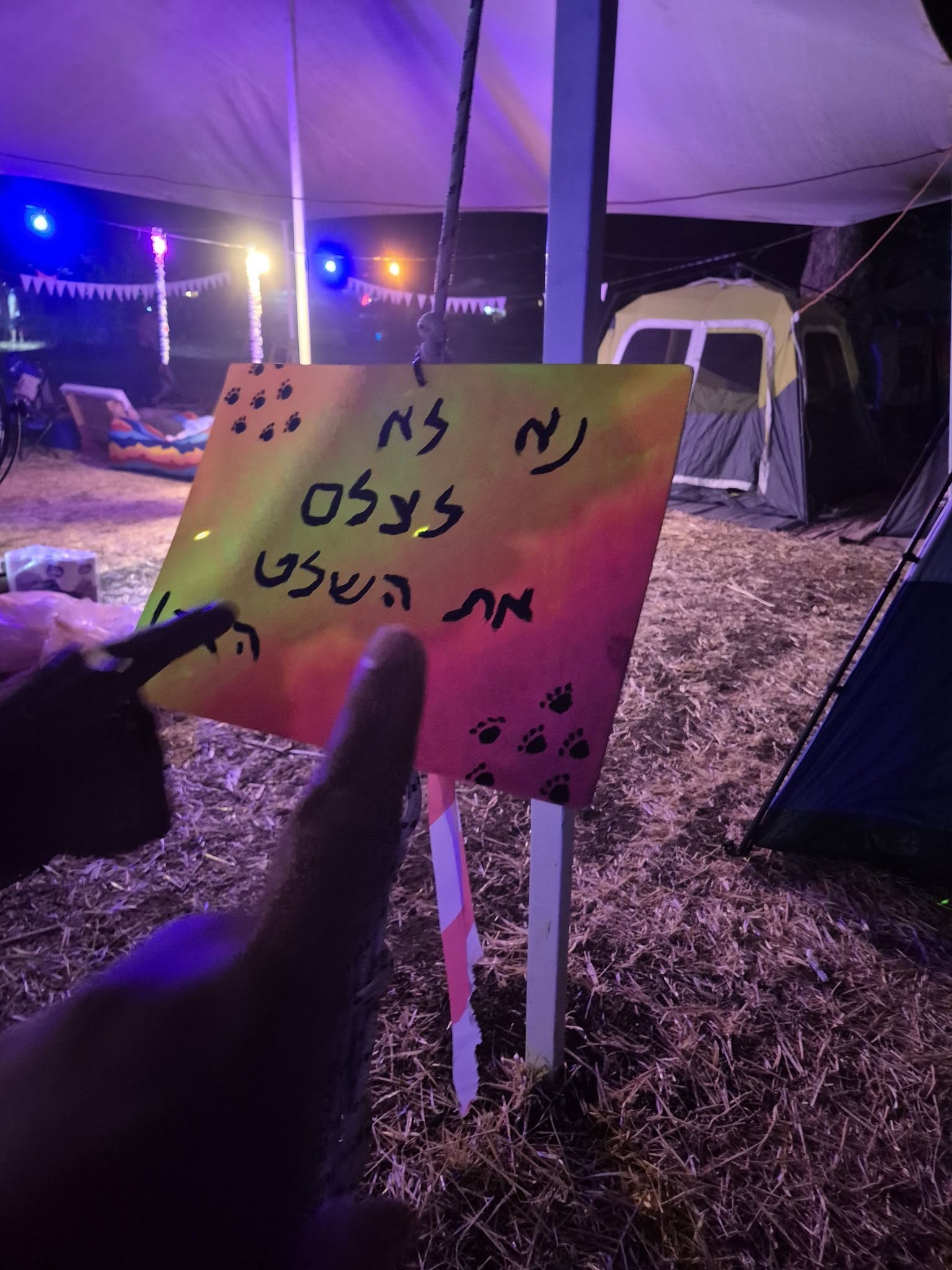 שלט ידני מוחזק בלילה מול מתחם הפסטיבל.