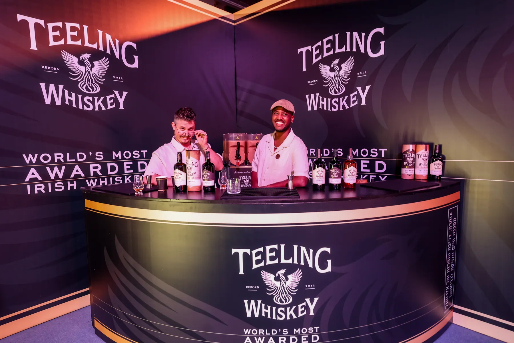 שני מציגים עומדים מאחורי דוכן Teeling Whiskey.